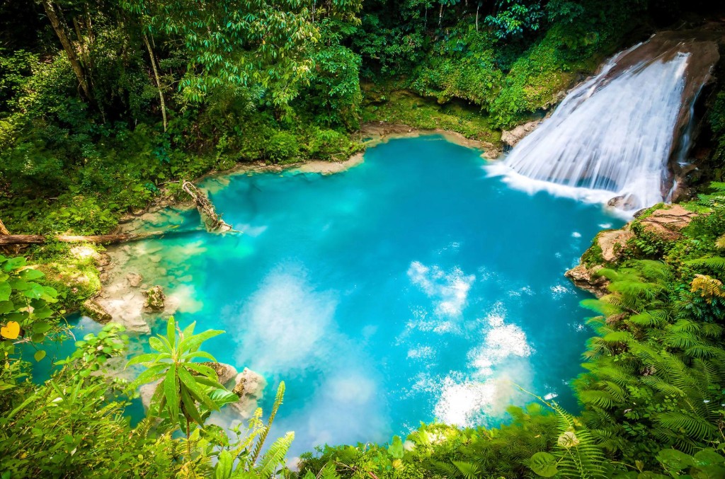 Turquoise Blue Hole lagoon with cascading waterfall and lush tropical rainforest on a Jamaica adventure shore excursion from Falmouth cruise port