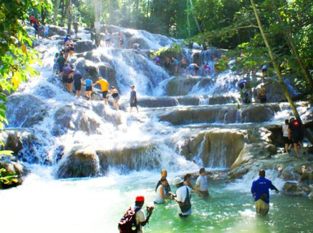 Cruise passengers climbing the terraced limestone rocks of Dunn's River Falls in Jamaica during a shore excursion from Falmouth cruise port