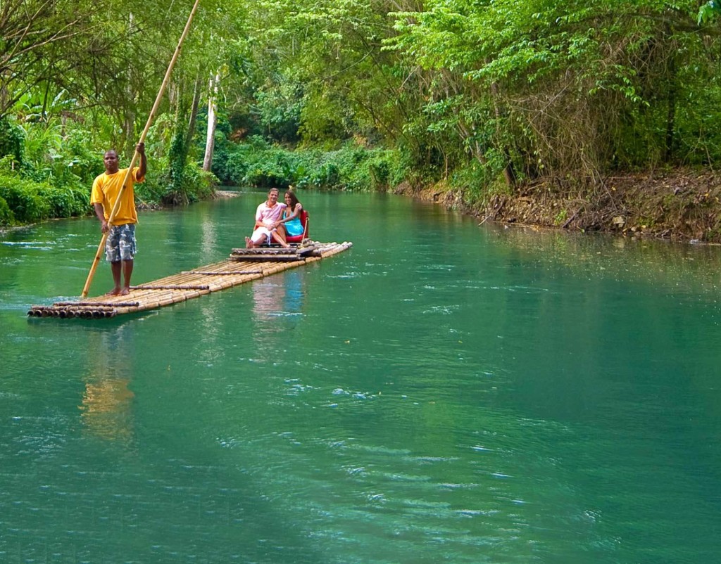 Cruise passengers enjoying a peaceful bamboo rafting tour on the turquoise Martha Brae River surrounded by lush tropical forest near Falmouth Jamaica cruise port